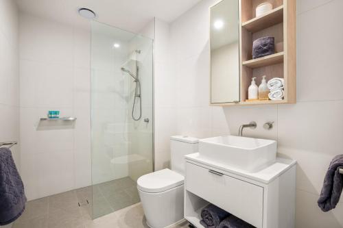 a white bathroom with a sink and a shower at 2BR Apartment in Geelong w/ Spectacular City View in Geelong