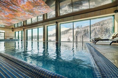 a swimming pool in a building with a mountain view at Hotel Pegaz in Krynica Zdrój