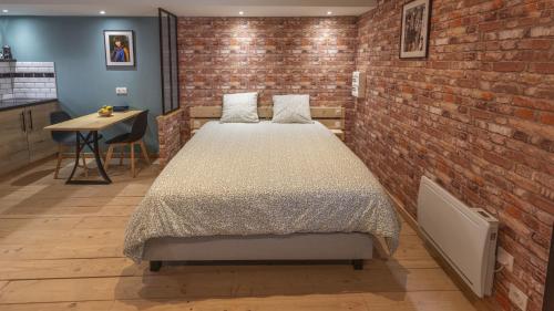 ein Schlafzimmer mit einem Bett und einer Ziegelwand in der Unterkunft L'Atelier Haute Couture in Le Mans