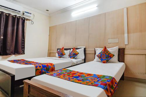 Habitación con 2 camas y almohadas coloridas. en FabHotel Nest Inn Service Apartment en Chennai