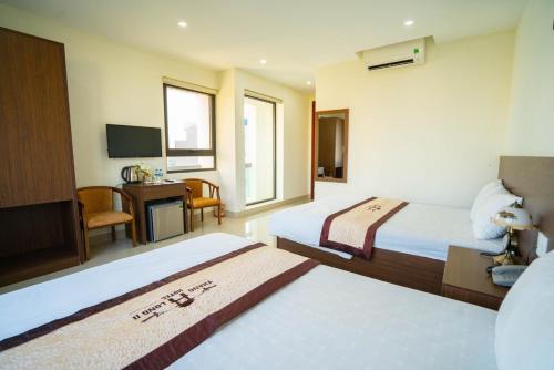 Habitación de hotel con 2 camas y escritorio en Thăng Long 2 Hotel FLC, en Lôc Hải