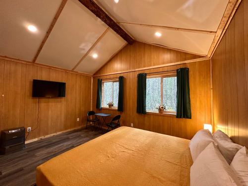 1 dormitorio con 1 cama y TV. en Roberts Lodge en Tok