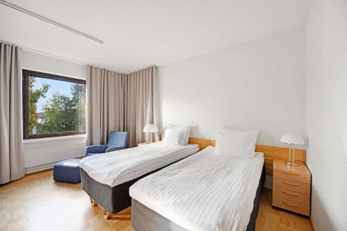 una habitación de hotel con 2 camas y una silla en Summer Hotel Tott, en Savonlinna