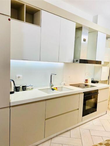 a kitchen with white cabinets and a sink at Onis Apartment in Vlorë