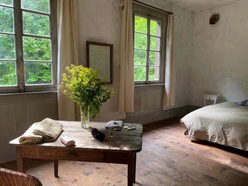 una camera da letto con un tavolo con un vaso di fiori sopra di Les anciens thermes a Soultzbach-les-Bains