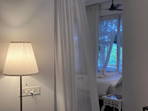um quarto com uma cama, um candeeiro e uma janela em Oceanic - Luxury Boutique Hotel em Palolem