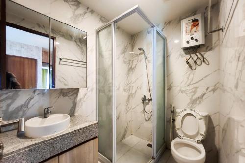 une salle de bain avec une douche, des toilettes et un lavabo dans l'établissement RedLiving Apartemen Grand Kamala Lagoon by Ownr Room, à Pekayon Satu