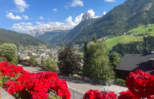 a view of a town and mountains with red flowers at B&B Lavi Ortisei val Gardena in Ortisei