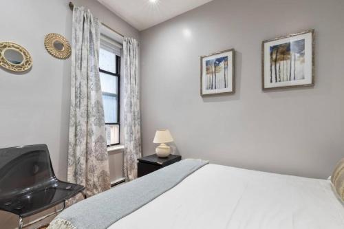 ein Schlafzimmer mit einem Bett, einem Stuhl und einem Fenster in der Unterkunft Spacious 4 Bedroom Apartment in New York