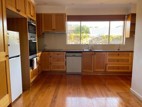 墨爾本的住宿－Home in Brighton，厨房配有木制橱柜、水槽和窗户。