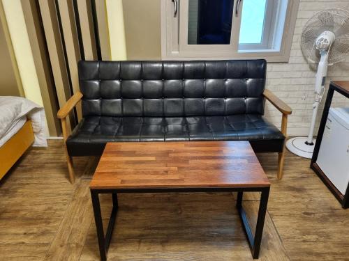 a black leather couch in a living room with a coffee table at Hwamyeong Sky Hotel in Busan