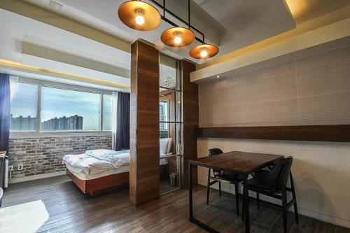 a bedroom with a bed and a desk and a table at Hwamyeong Sky Hotel in Busan