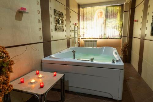 a bathroom with a tub with candles on a table at Почивен комплекс Минкови бани in Spantschewzi