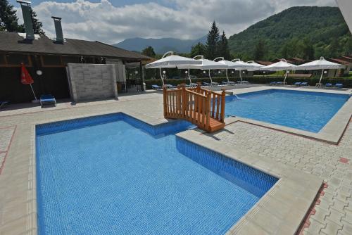 a large blue swimming pool with umbrellas at Почивен комплекс Минкови бани in Varshets