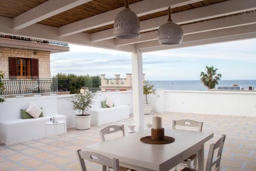 un patio con mesa, sillas y el océano en Al Porticciolo di Savelletri, en Savelletri di Fasano