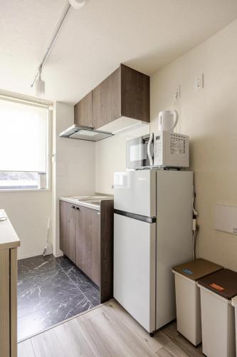 a kitchen with a white refrigerator and wooden cabinets at リリハウス笹塚 in Tokyo