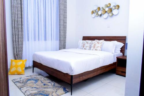 - une chambre avec un lit doté de draps et d'oreillers blancs dans l'établissement Amalia Apartments Syokimau, à Machakos
