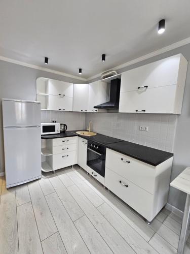 a kitchen with white cabinets and a white refrigerator at Двухкомнатная квартира на Ауезова in Kokshetau