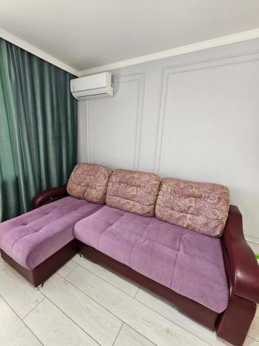 un sofá púrpura en una sala de estar con cortinas verdes en Двухкомнатная квартира на Ауезова, en Kokshetau