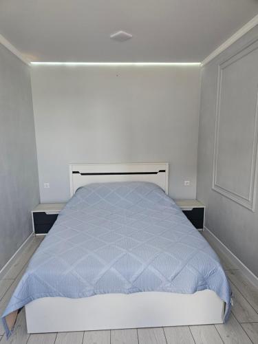un letto bianco in una camera da letto con parete bianca di Двухкомнатная квартира на Ауезова a Kökşetaw
