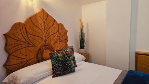 a bed with a large wooden headboard in a room at Pension Paloma - Oiartzun in Oiartzun