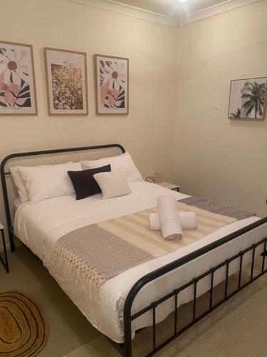 um quarto com uma cama com lençóis brancos e almofadas em Riverside Boutique Apartment em Rockhampton