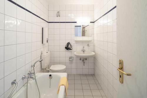 a white tiled bathroom with a toilet and a sink at Fewo am Edersee mit 2 Schlafzimmern in Scheid