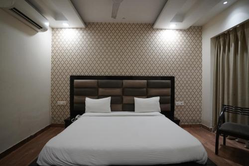 um quarto com uma grande cama branca e uma cadeira em Nirmal Hotel And Resort em Bareilly