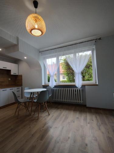 ein Wohnzimmer mit einem Tisch, Stühlen und einem Fenster in der Unterkunft Apartament na Mazurach -Ryn in Ryn