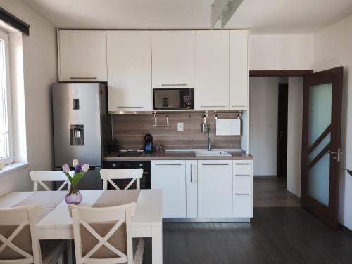 a kitchen with white cabinets and a table with chairs at Happy Apartment & Free Breakfast - Mladost in Sofia