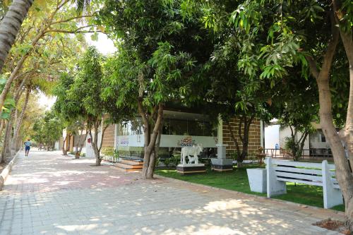 a sidewalk with benches and trees in front of a building at ARS FARMSTAY in Munirābād