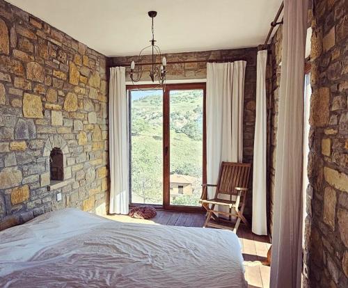 a bedroom with a stone wall with a bed and a chair at Villa Toscana in Gokceada Town