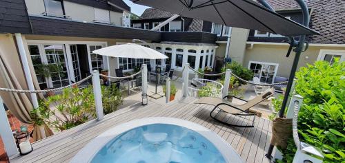 una terraza al aire libre con bañera de hidromasaje y sombrilla en Strandhaus an der Mosel en Valwig