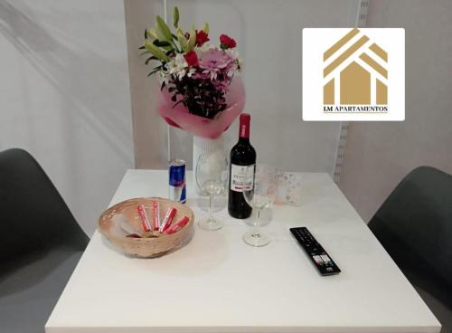 ein Tisch mit einer Flasche Wein und einer Vase mit Blumen in der Unterkunft LM apartments Puentezuelas in Granada