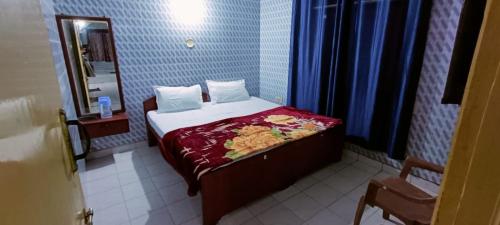 a small bedroom with a bed and a mirror at Misty Meadows in Ooty