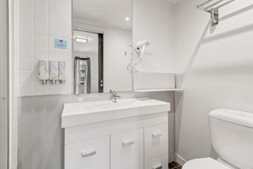 a white bathroom with a sink and a toilet at Central Melbourne CBD Apartment by Crown Casino in Melbourne