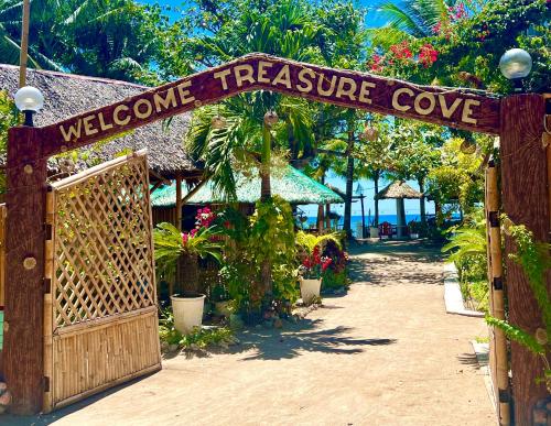 a welcome treearine cove sign over a wooden gate at Treasure Beach in Carles