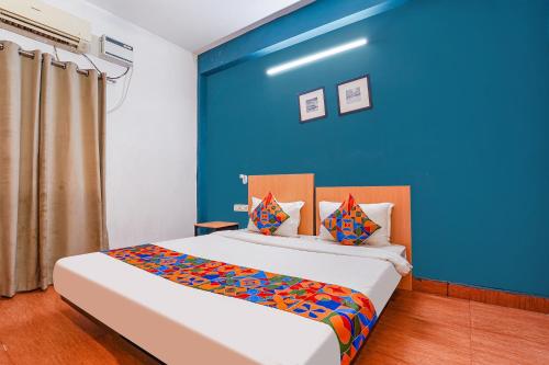 Duas camas num quarto com uma parede azul em FabExpress Harma Residency em Chennai