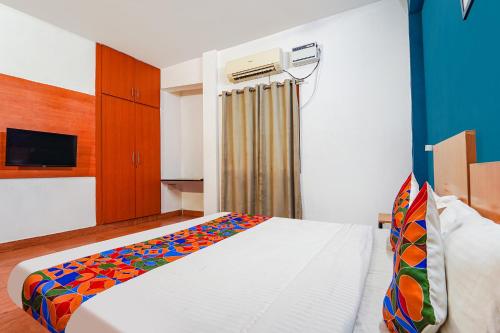 ein Schlafzimmer mit einem weißen Bett mit einer bunten Decke in der Unterkunft FabExpress Harma Residency in Chennai