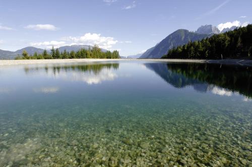 a large body of water with trees and mountains at Familienhotel Moos-Alm in Lienz