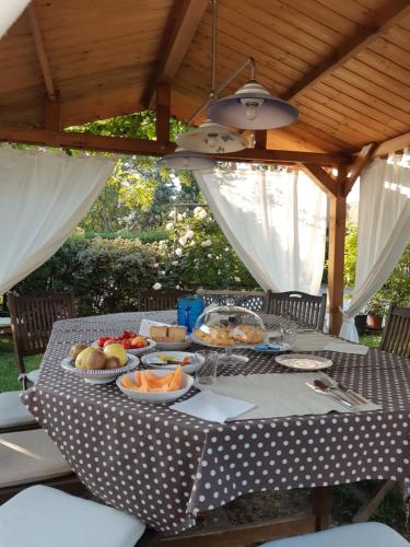 a picnic table with food on it under a roof at La Casa di Biba in Massa Lombarda