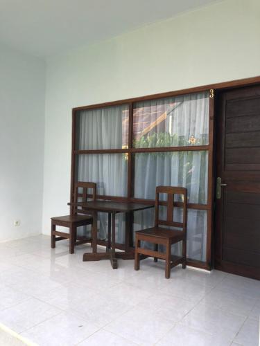 a wooden table and two chairs and a door at Maha di Nusa Lembongan in Nusa Lembongan
