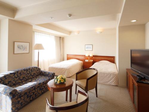 um quarto de hotel com um sofá e uma televisão em Hotel Crown Palais Kokura em Kitakyushu