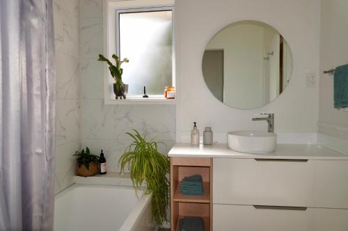 Baño blanco con lavabo y espejo en Comfortable Home, Big Backyard, en Rotorua