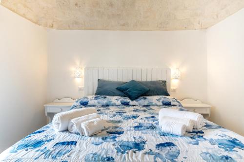 a blue and white bed with two pillows on it at Trullo degli Anelli in Masseria in Cisternino