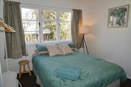 a bedroom with a bed and two windows at Comfortable Home, Big Backyard in Rotorua