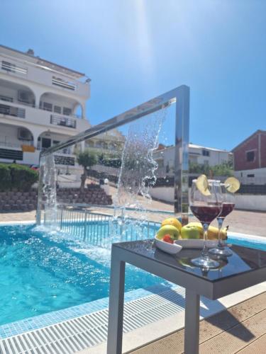 a table with a glass of wine next to a swimming pool at Apartments Silva in Trogir