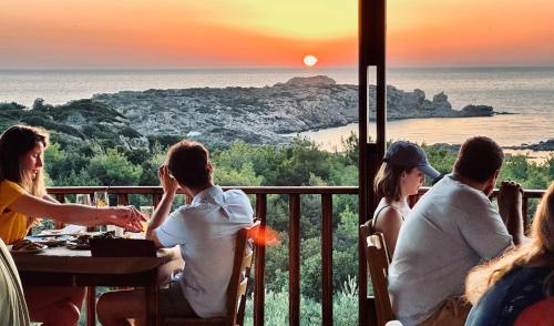 Un gruppo di persone sedute a un tavolo a guardare il tramonto di Glykeria Hotel a Elafonisi