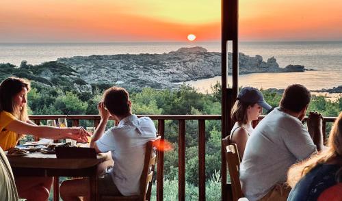 een groep mensen die aan een tafel zitten en naar de zonsondergang kijken bij Glykeria Hotel in Elafonisi
