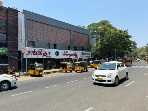 un coche blanco conduciendo por una calle frente a un edificio en Sangeetha Business Hotel, en Chennai